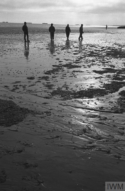 Vétérans marchant sur la plage à Arromanches