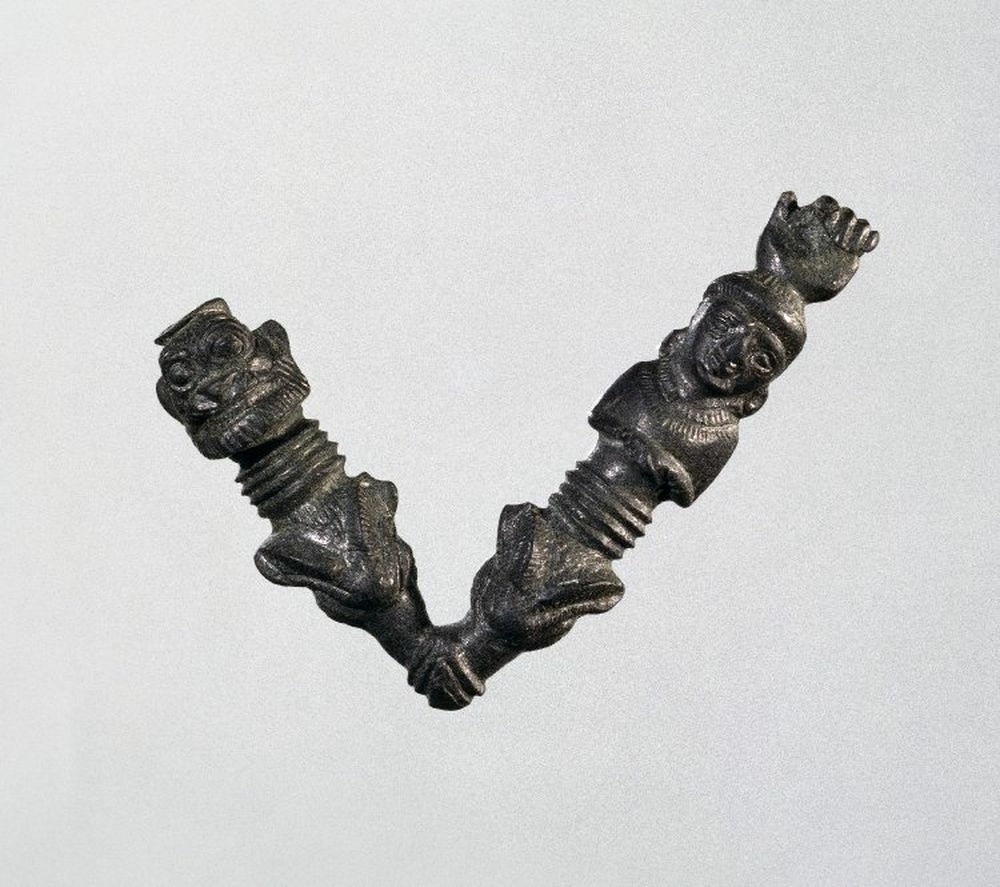 Fibule décorée avec une tête de Pazuzu et une tête de femme.