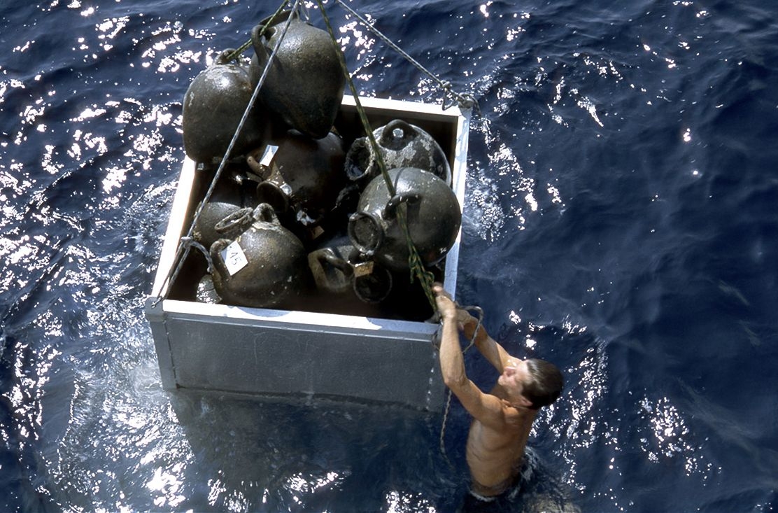 Photographie d'un archéologue-plongeur remontant les objets à la surface