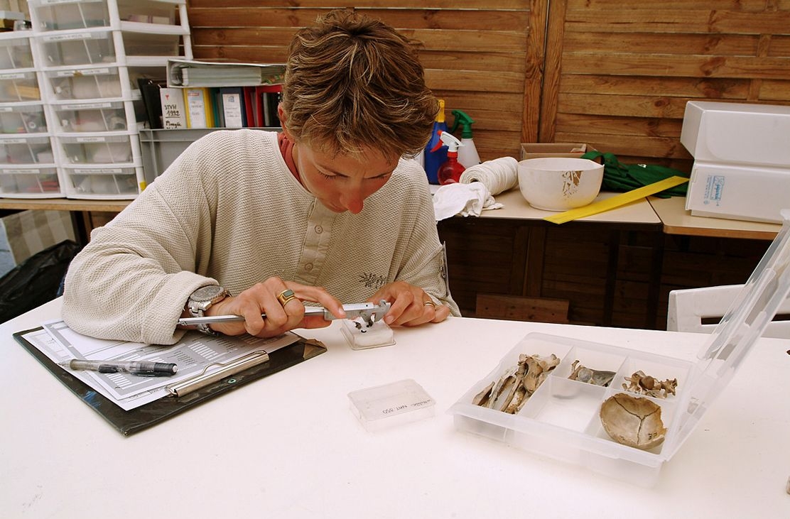 Photographie d'un archéologue prenant les mesures d'un objet