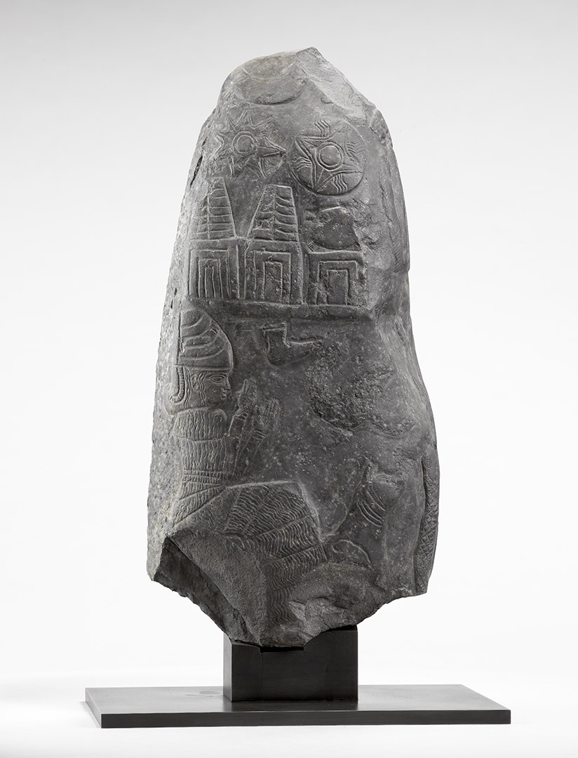 Stèle en pierre représentant la déesse de la médecine et un chien assis, surmontés des symboles divins.