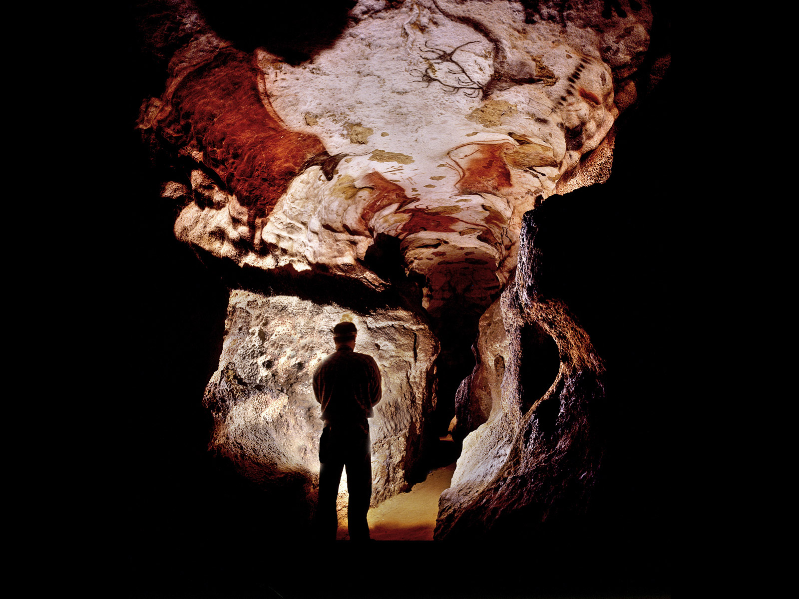 Photographie de Norbert Aujoulat, de dos, à l'entrée du Diverticule axial de la grotte de Lascaux.