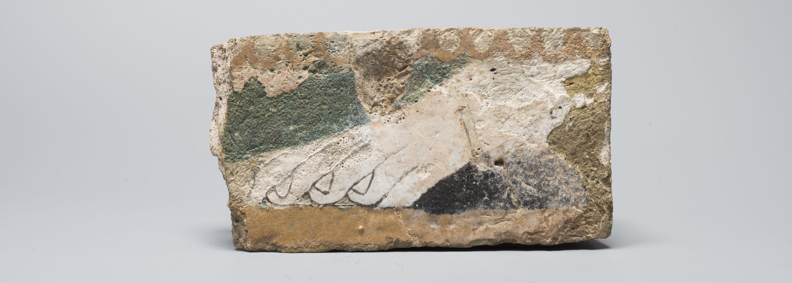 Fragment de décor : brique ornée d'un pied