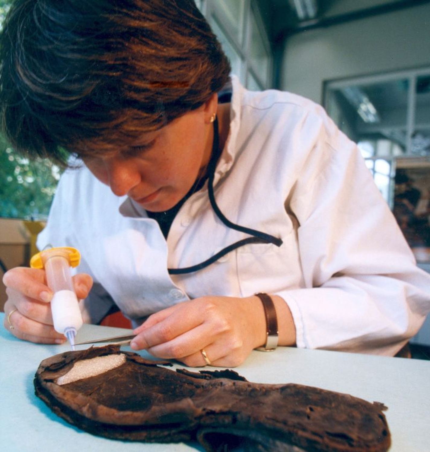Photographie d'une archéologue étudiant la semelle d'une chaussure